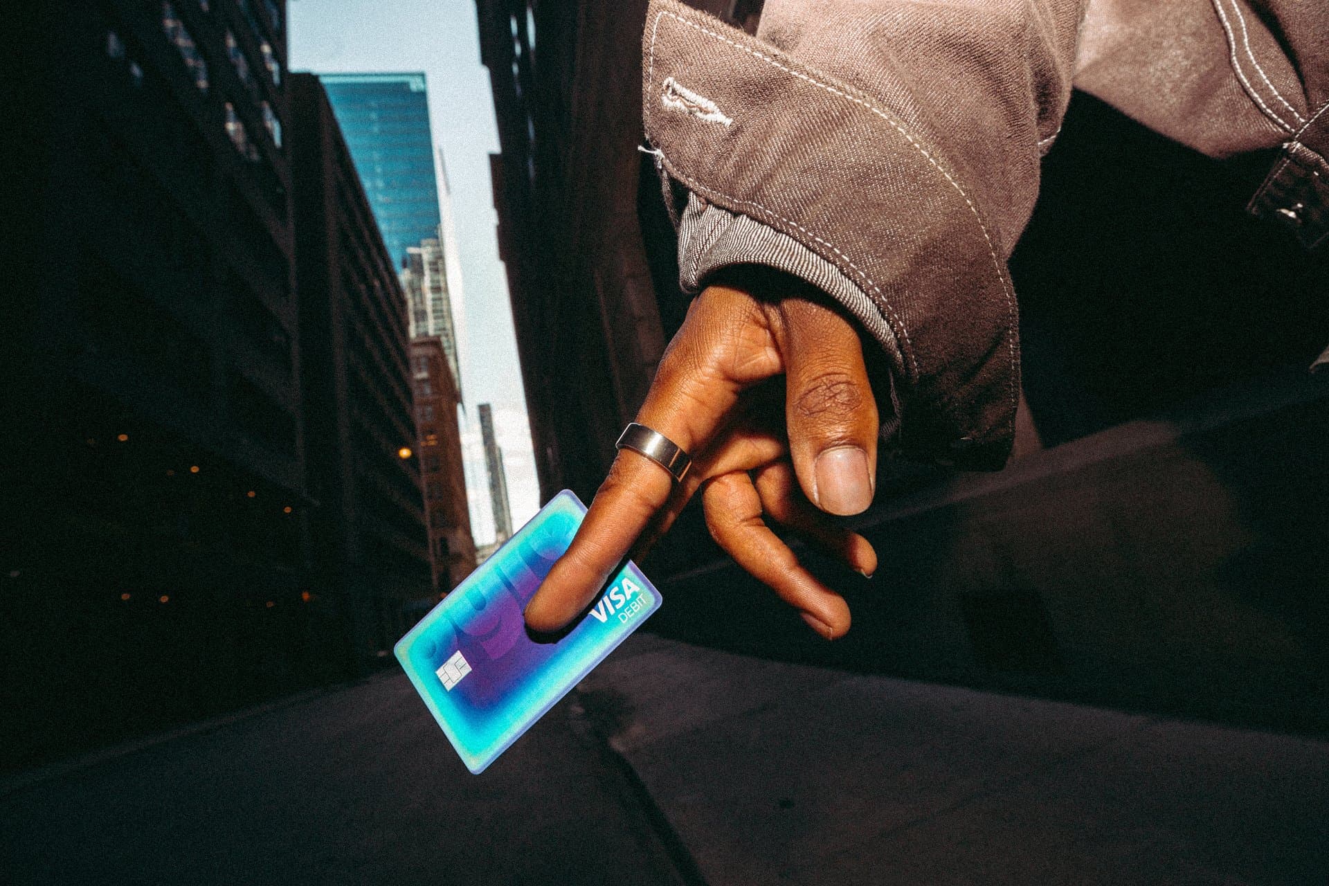 Pyre lifestyle concept showing a hand holding a colorful payment card on a city street